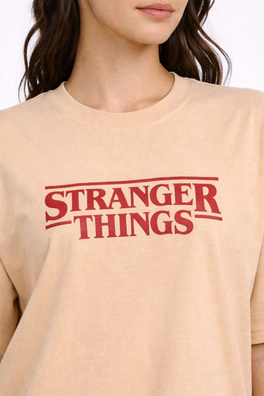 Beige oversized  t-shirt with 'Stranger Things' logo worn by a person