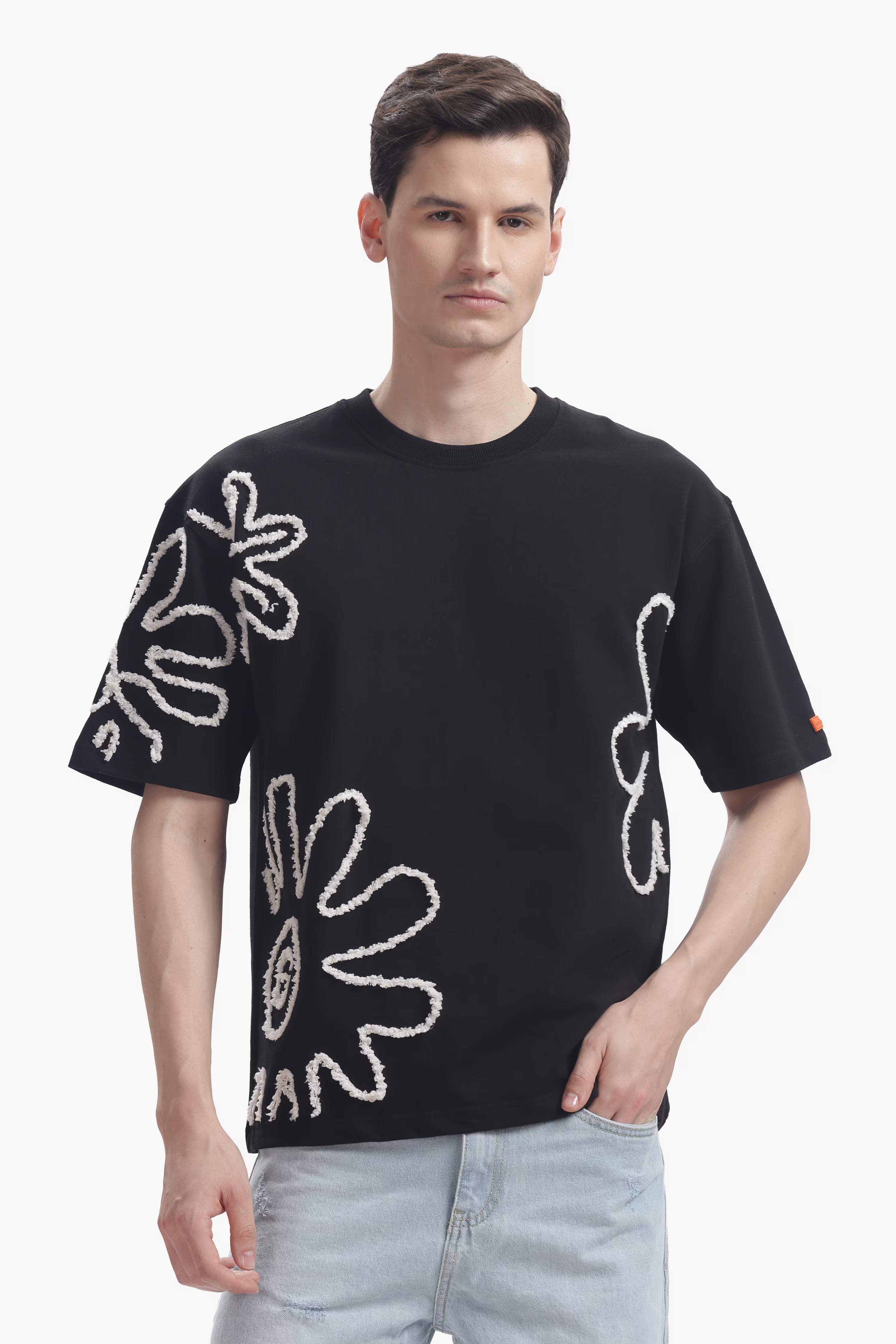 Man wearing a black t-shirt with white floral patterns on a white background