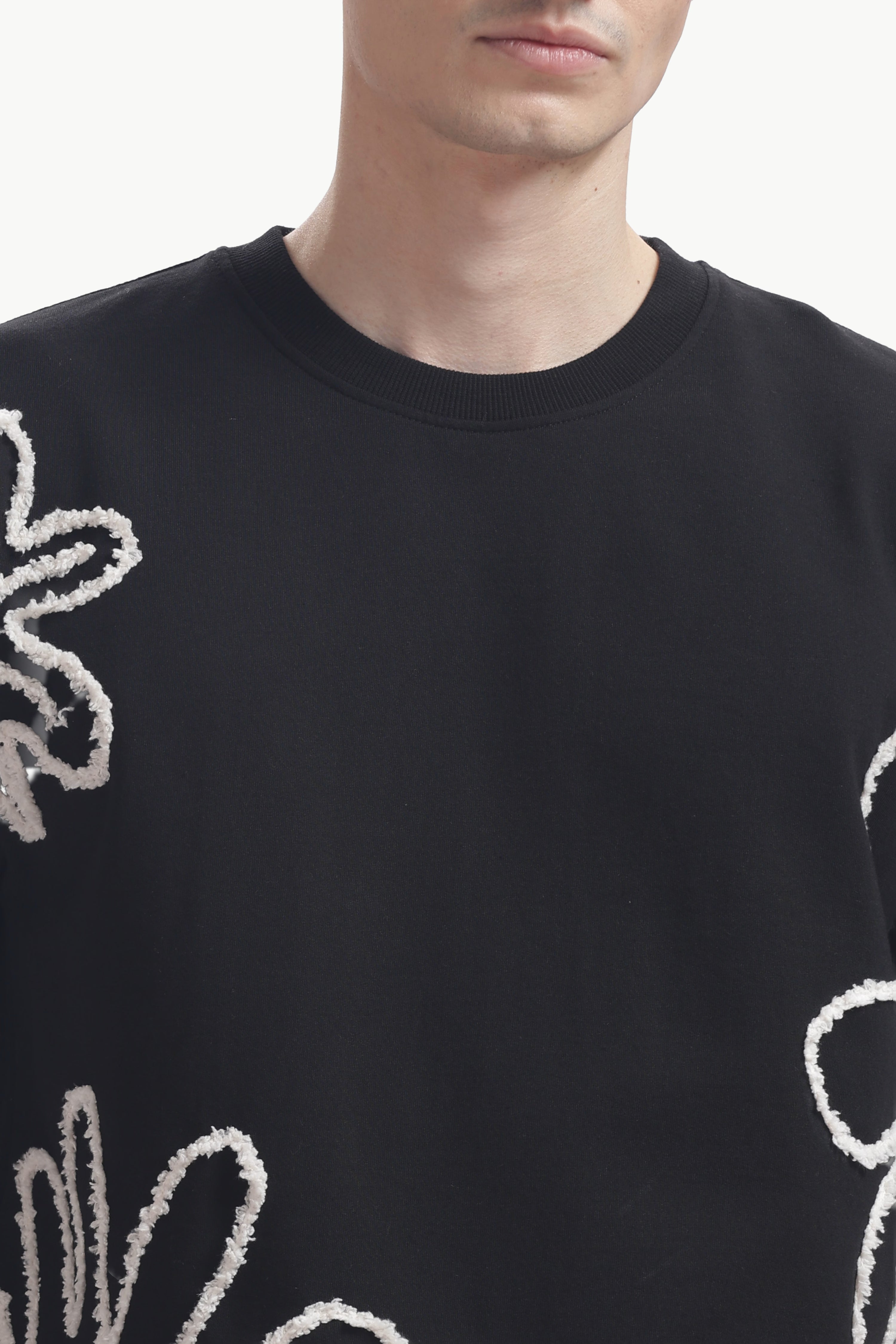 Black sweater with white floral patterns worn by a person