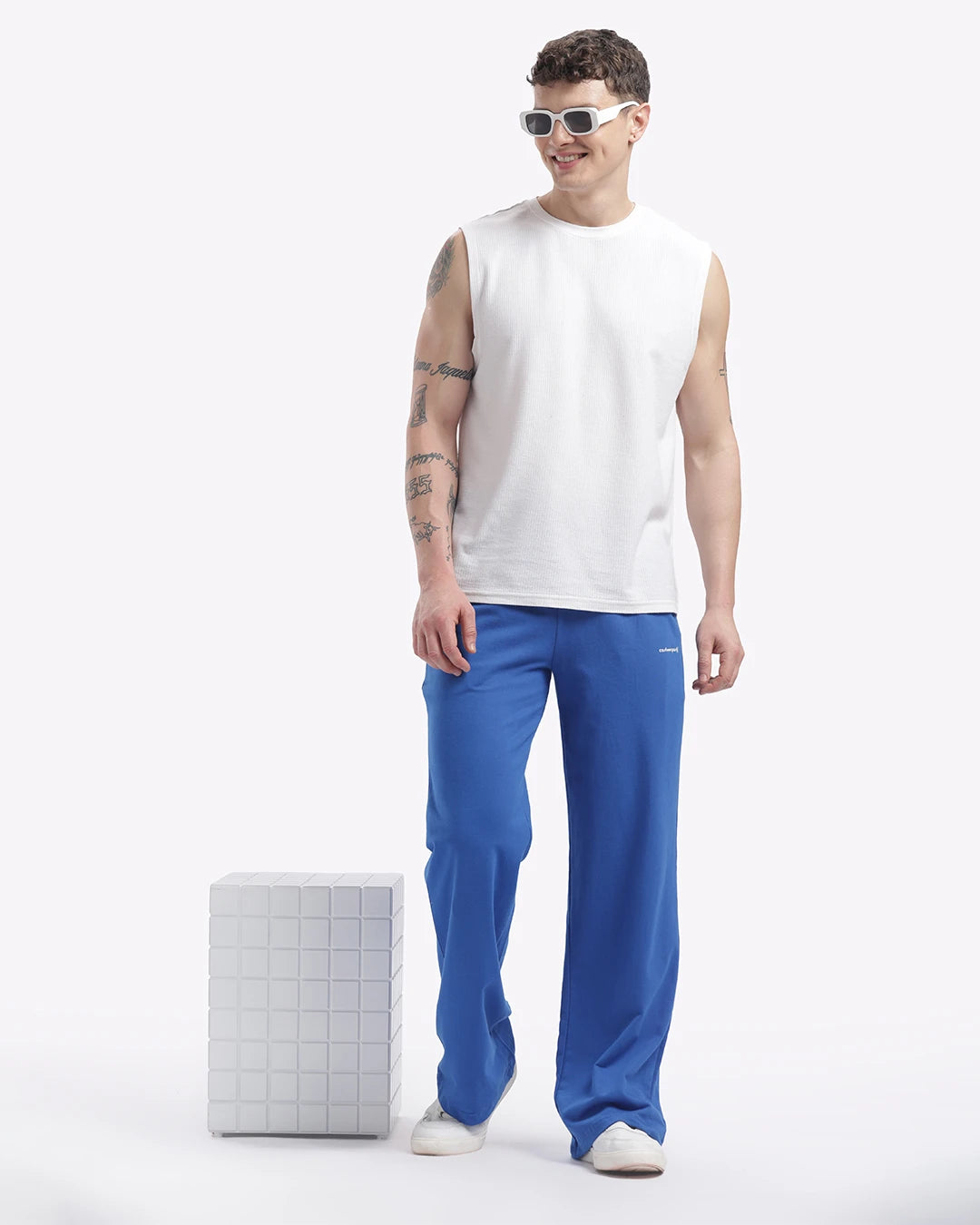 Person wearing a white sleeveless shirt and blue pants on a white background