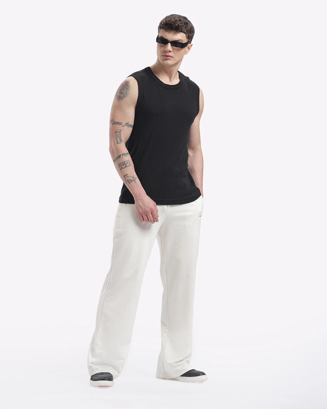 Person wearing a black sleeveless shirt and white pants on a white background