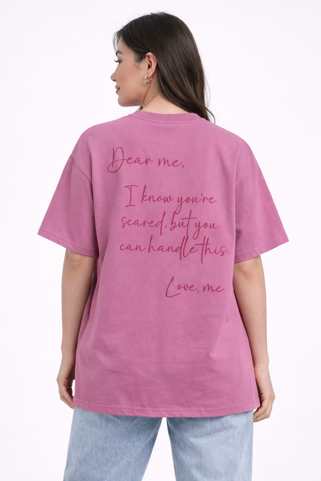 Person wearing a pink t-shirt with a motivational quote on the back, standing against a white background.