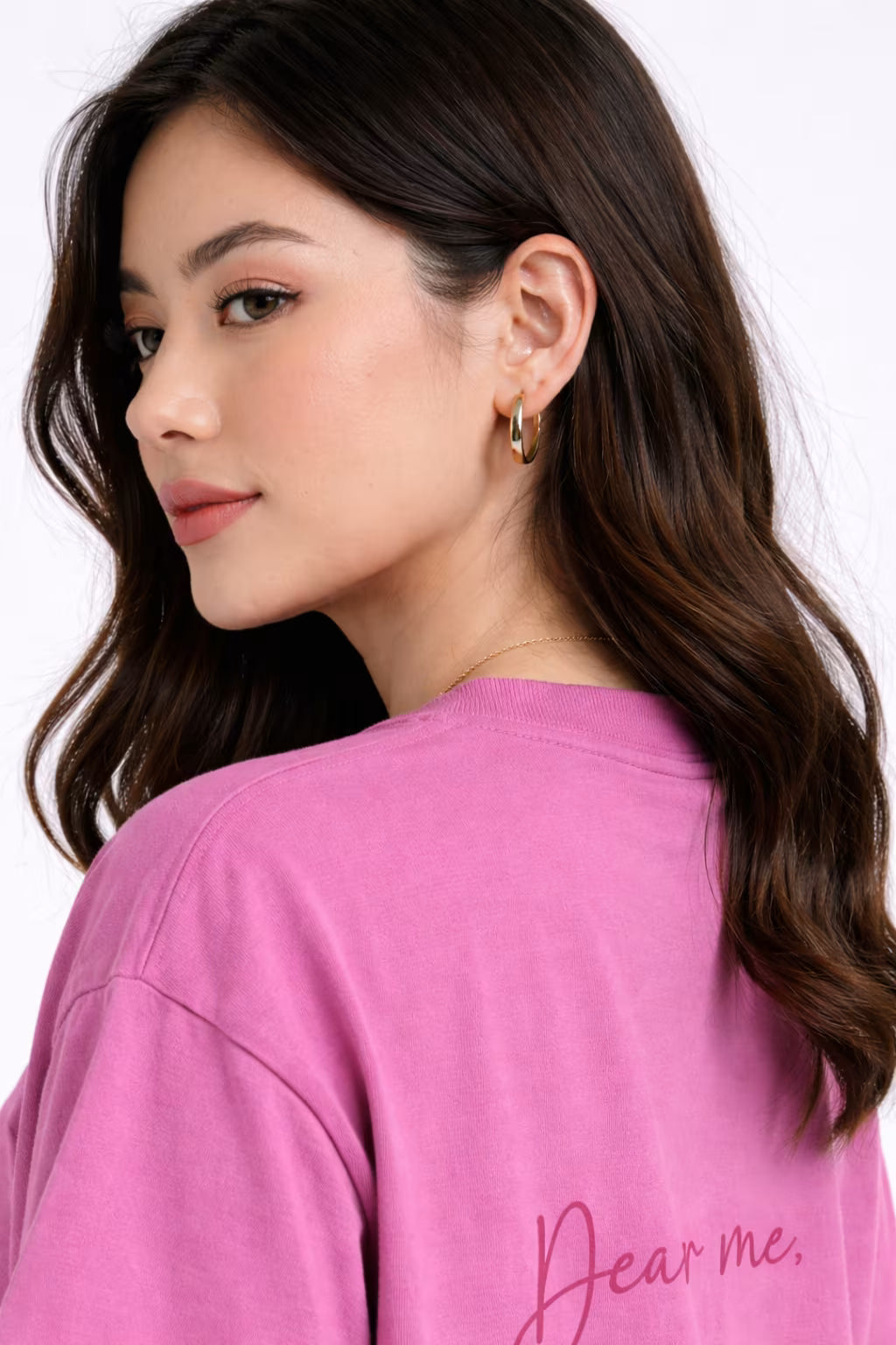 Woman wearing a pink shirt with 'Dear me.' text on a white background