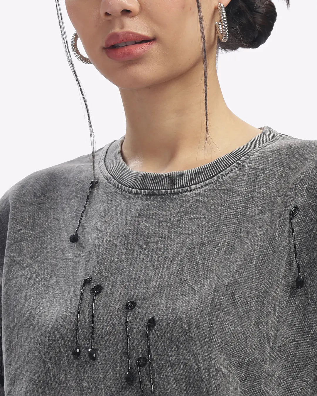 Close-up of a person wearing a gray textured sweater with black buttons.