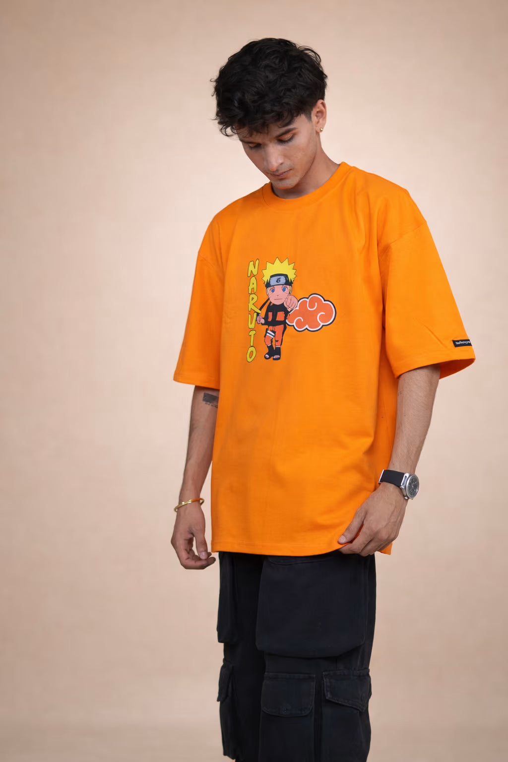 Person wearing an orange t-shirt with a graphic design on a beige background