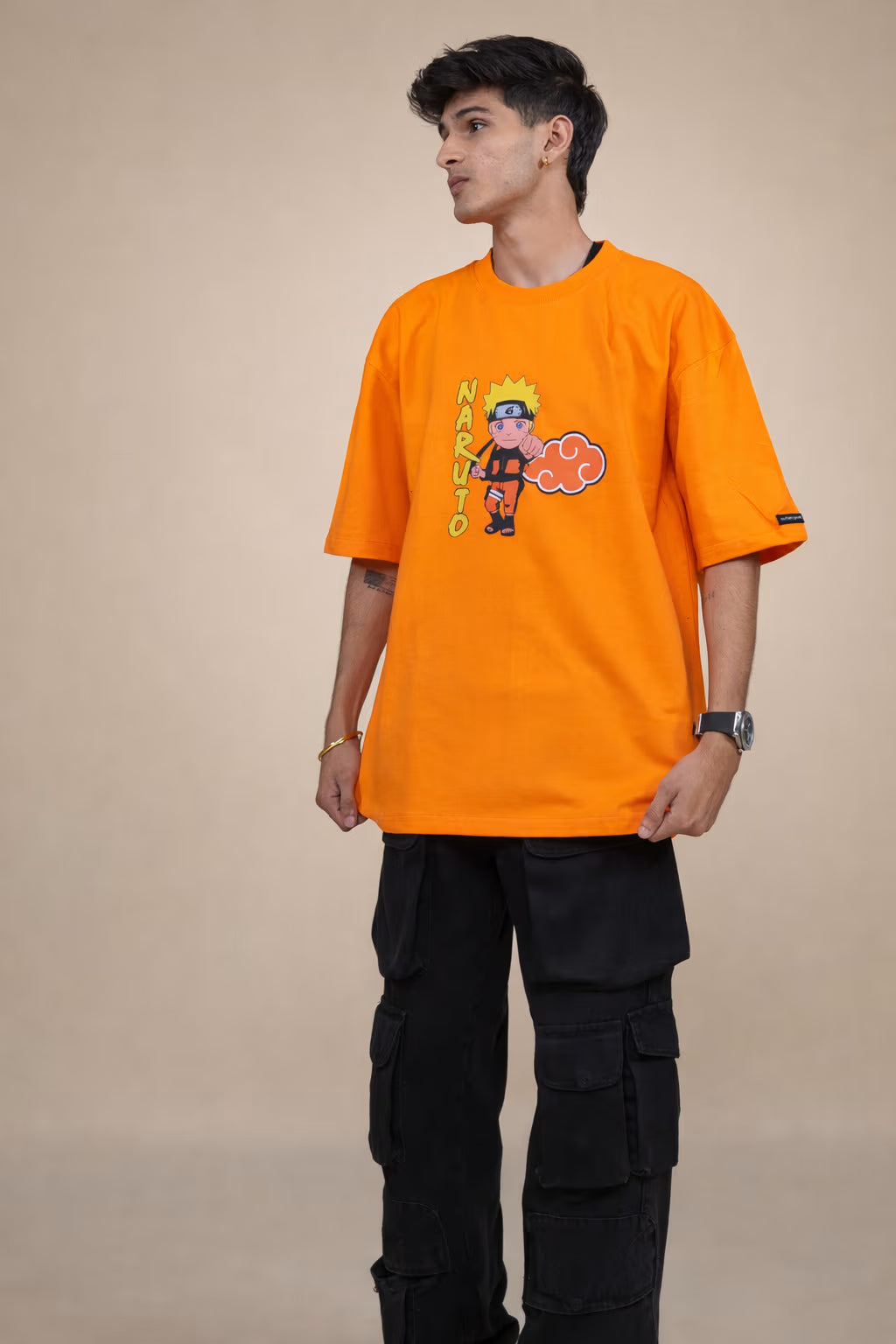 Person wearing an orange t-shirt with a graphic design on a beige background