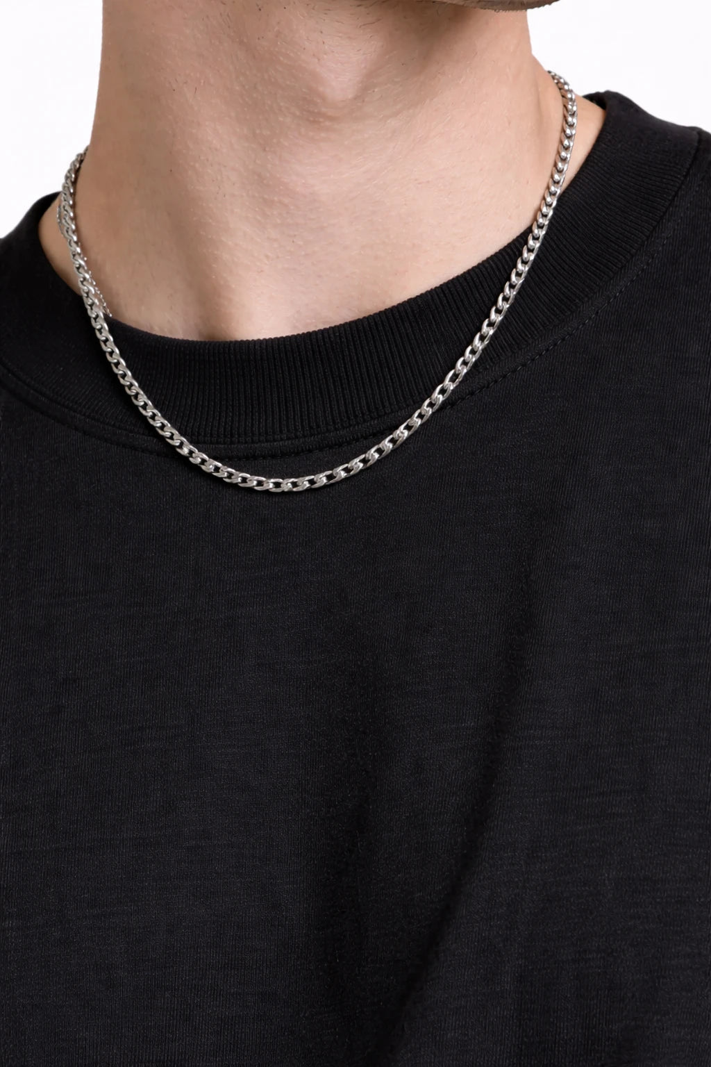 Person wearing a silver chain necklace on a plain background