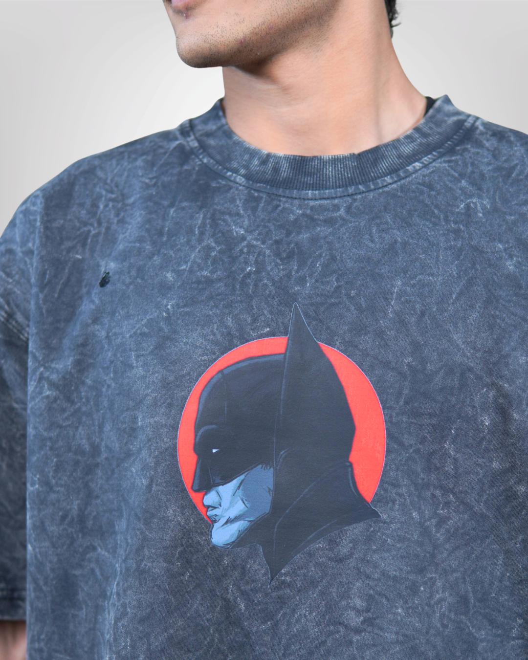 Person wearing a acid grey bat man graphic t-shirt with a prominent design on the back.