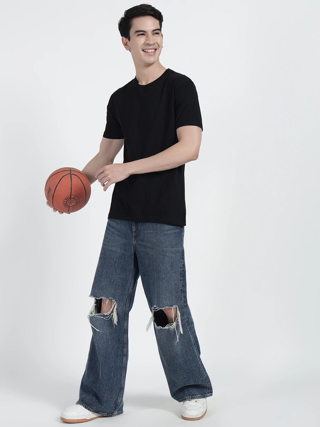A person standing and holding a basketball, wearing a black plain T-shirt by cartonpanti india