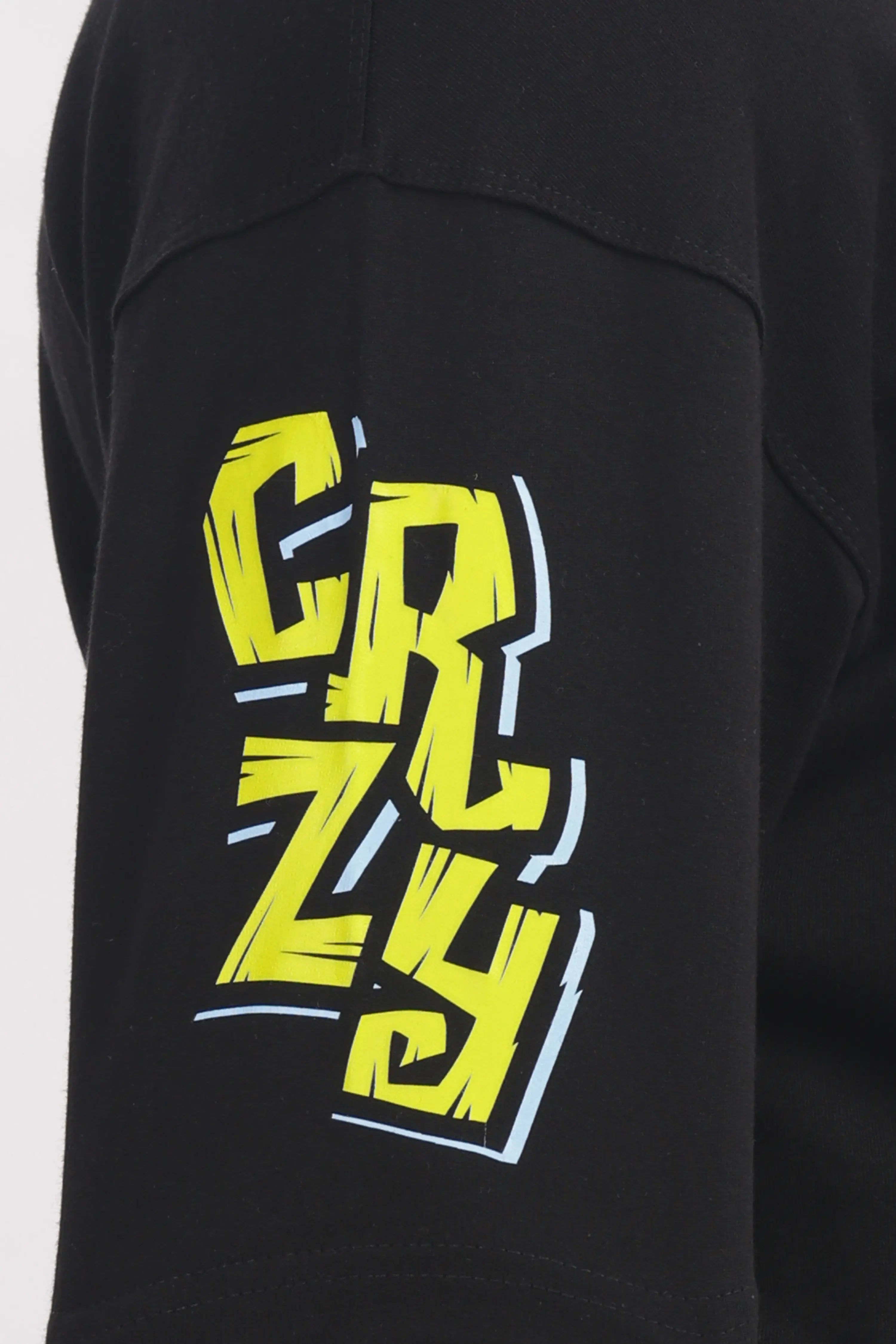 Person wearing a black t-shirt with colorful graphics BE Brave and light gray pants on a white background