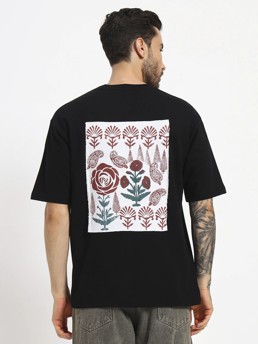 Person wearing a black oversized t-shirt with a floral pattern   cartoonpanti by india