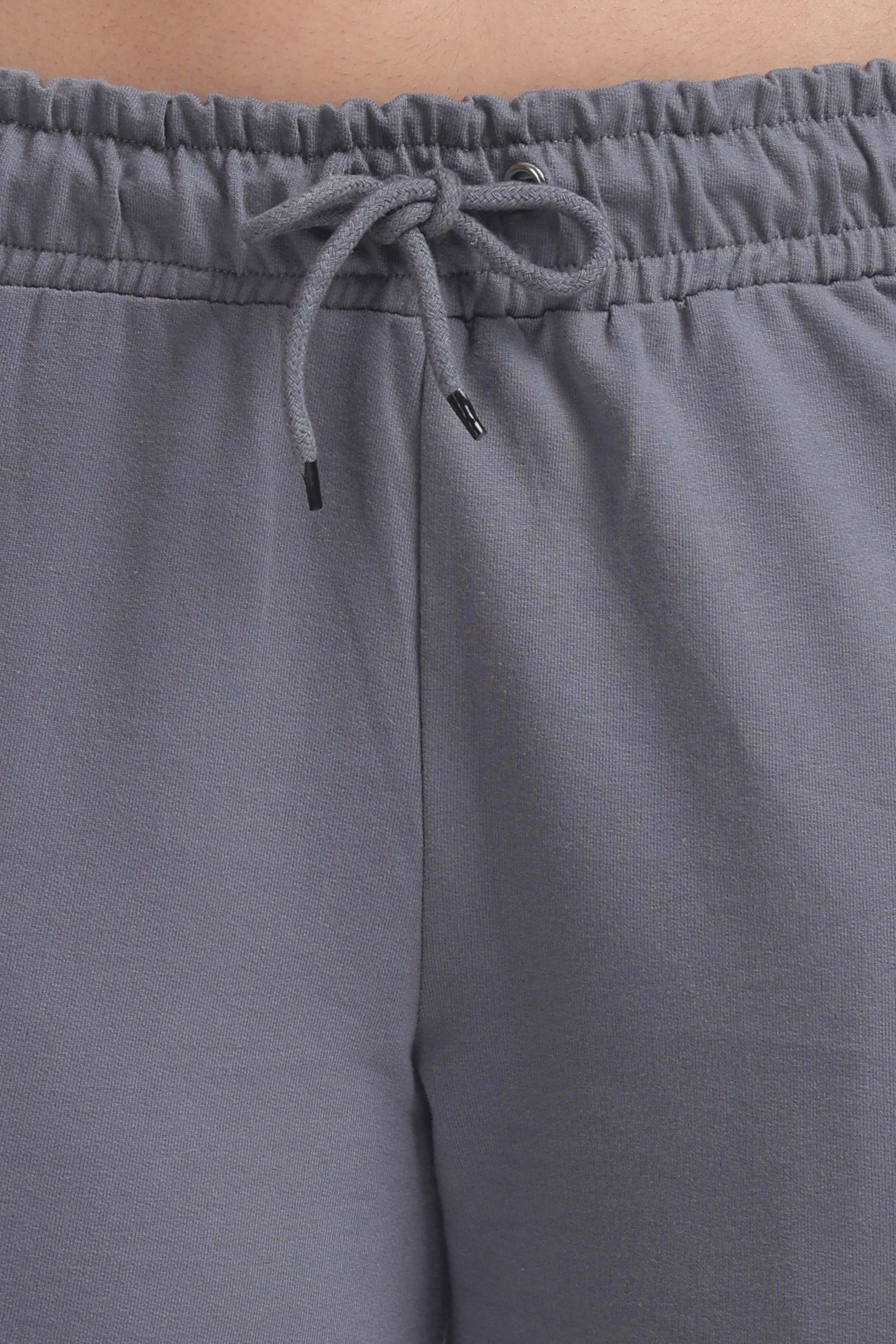 Gray sweatpants with a drawstring waistband on a neutral background