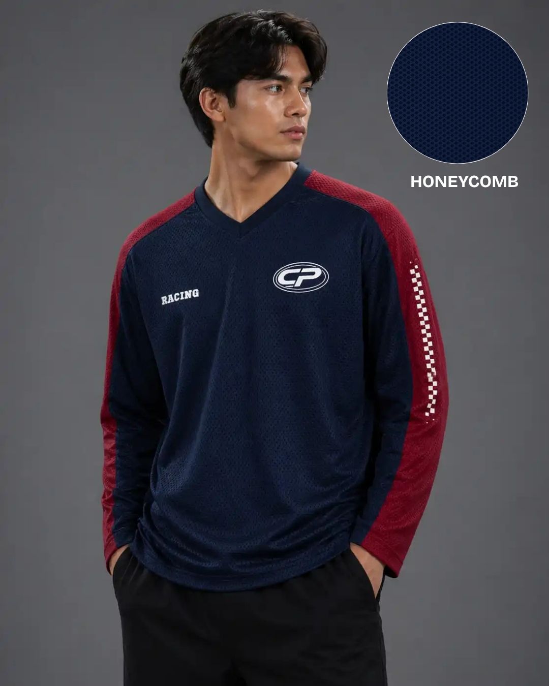 Man wearing a navy and red long-sleeve shirt with a logo on a gray background
