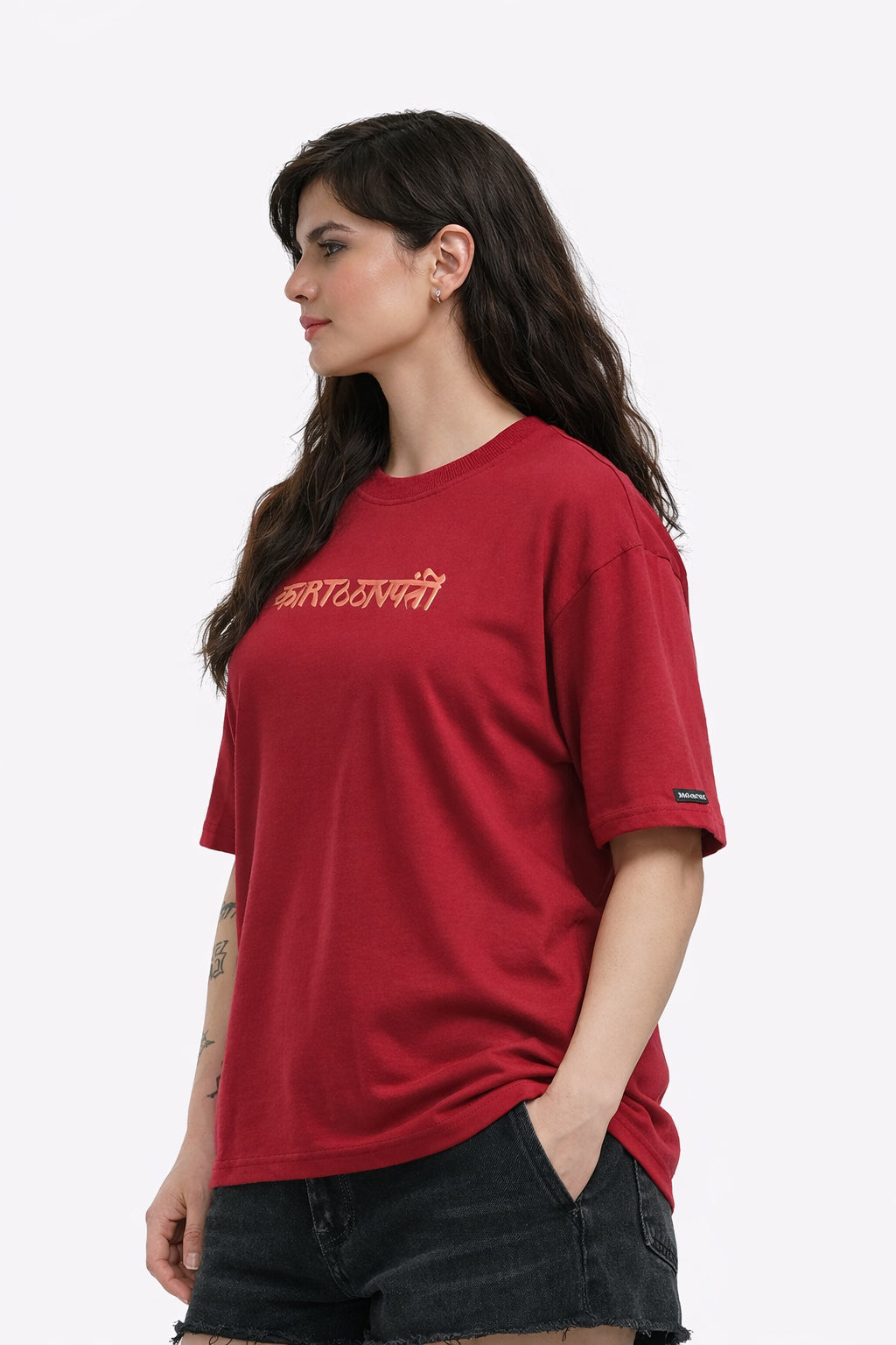 Person wearing a mahroon T-shirt with a graphic design madhubani on the back, standing against a white background