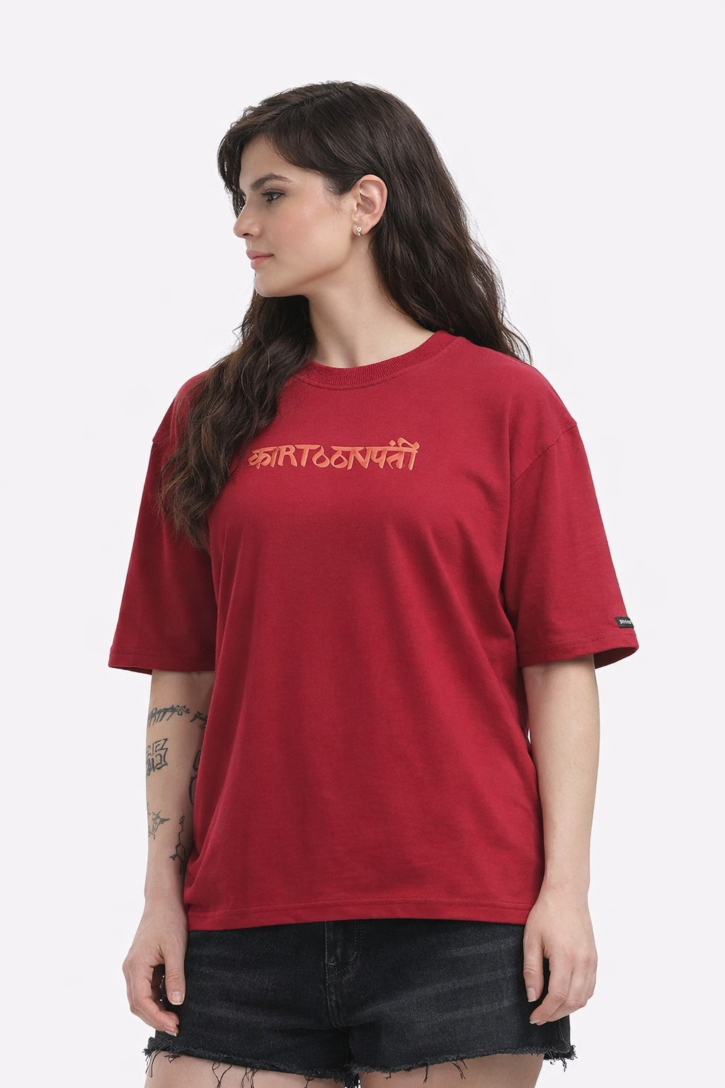 Person wearing a mahroon T-shirt with a graphic design madhubani on the back, standing against a white background