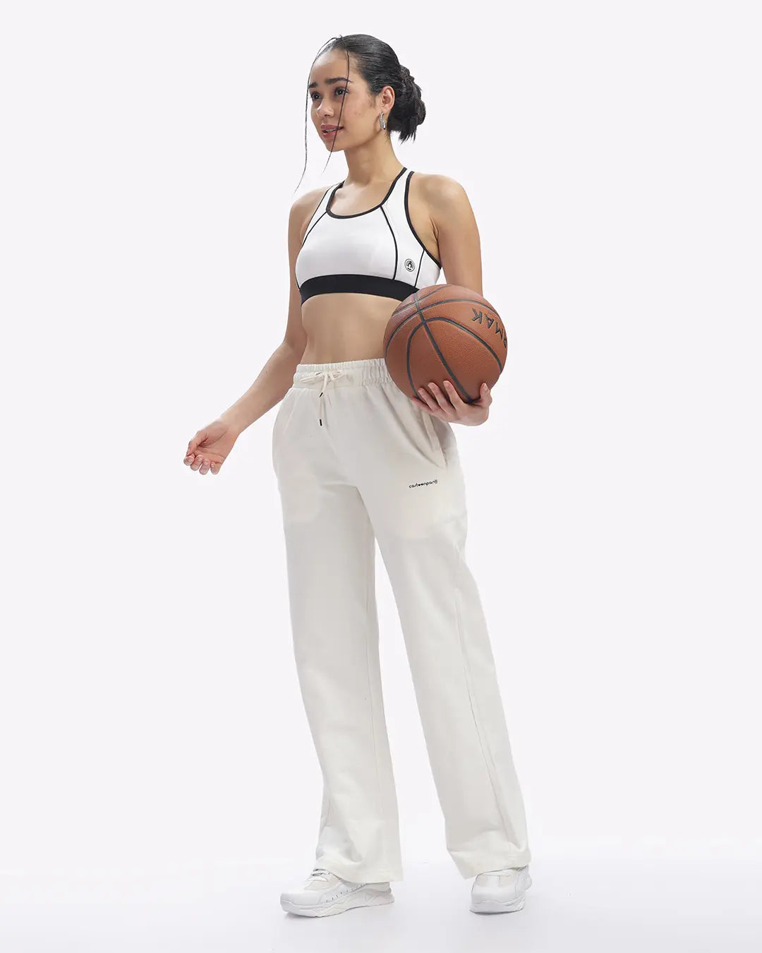 Woman holding a basketball wearing a sports outfit on a white background