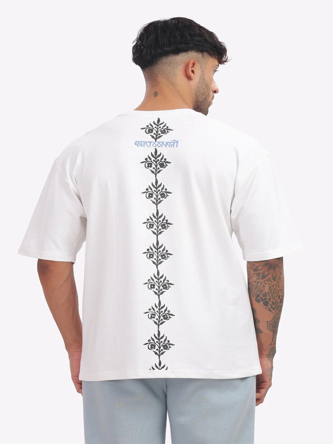 Person wearing a white t-shirt with black floral patterns on the back, standing against a white background.